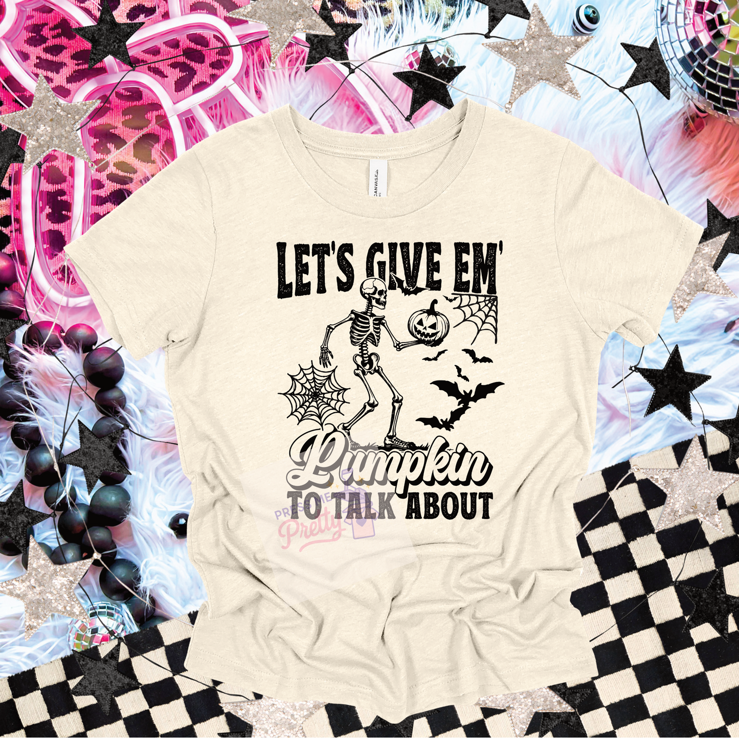Beige t-shirt with Halloween-themed text and graphics on a colorful, patterned background.