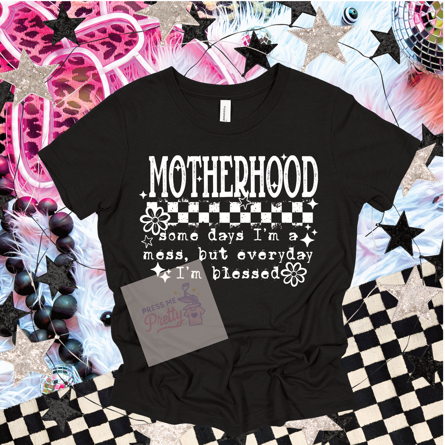 Black t-shirt with 'Motherhood' text design on a decorative background